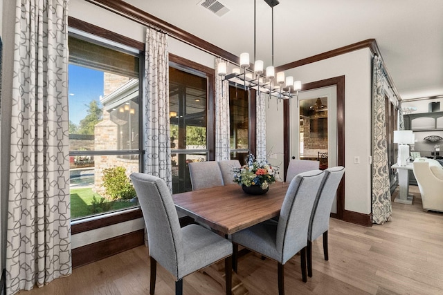 dining room featuring ornamental molding, an inviting chandelier, and light wood-type flooring