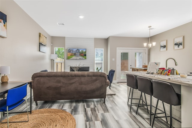 living room with light hardwood / wood-style floors, a healthy amount of sunlight, a chandelier, and french doors