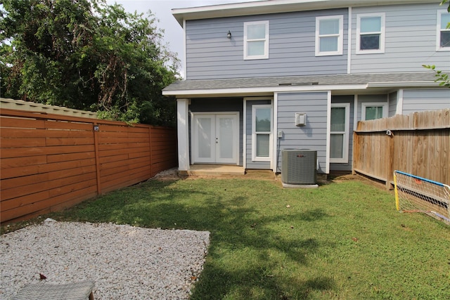 back of property featuring french doors, a yard, and central AC unit