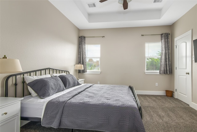 bedroom featuring a raised ceiling, dark colored carpet, and ceiling fan