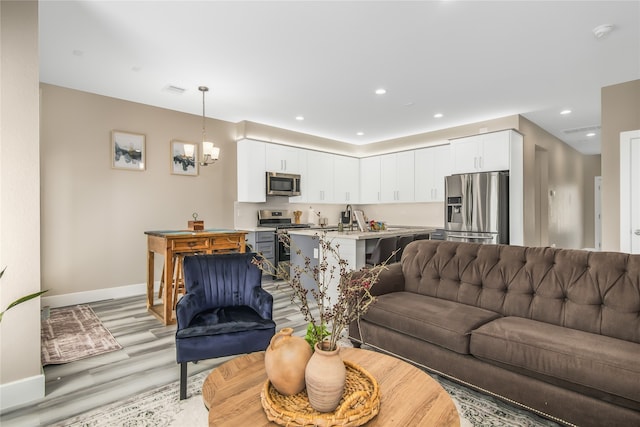 living room with an inviting chandelier and light hardwood / wood-style floors