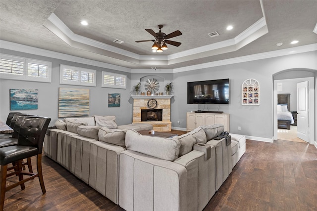 living room with dark wood-type flooring, ornamental molding, and a tray ceiling