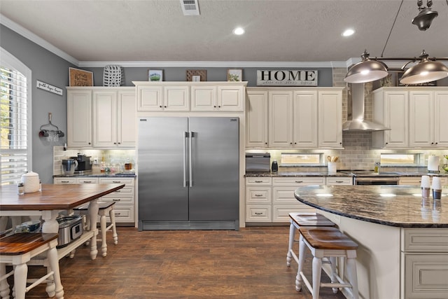 kitchen featuring tasteful backsplash, white cabinetry, appliances with stainless steel finishes, and wall chimney exhaust hood