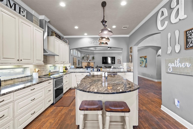 kitchen with white cabinetry, double oven range, dark stone countertops, decorative backsplash, and kitchen peninsula