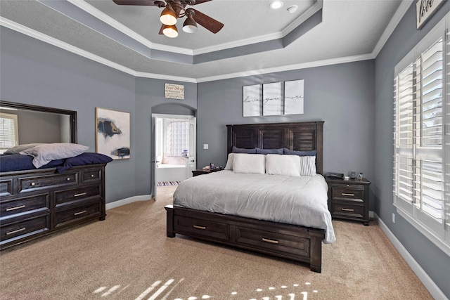 carpeted bedroom featuring ceiling fan, ensuite bathroom, a raised ceiling, and ornamental molding