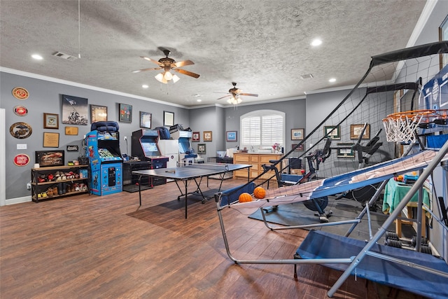 recreation room with hardwood / wood-style flooring, crown molding, ceiling fan, and a textured ceiling