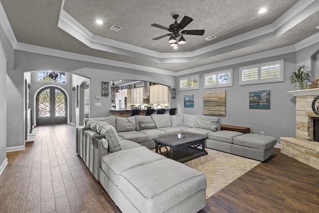 living room with french doors, dark hardwood / wood-style flooring, a raised ceiling, and crown molding