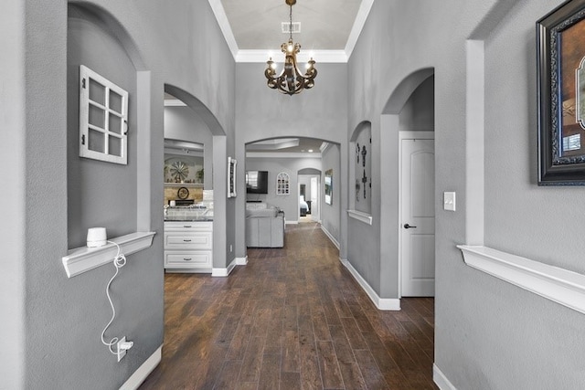 hall with ornamental molding, dark hardwood / wood-style floors, and a notable chandelier