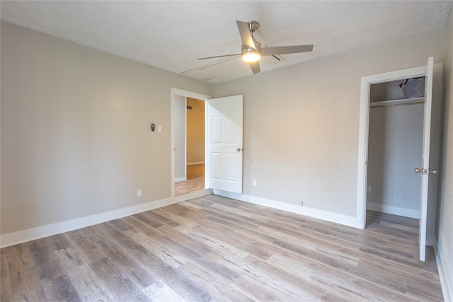 unfurnished bedroom featuring ceiling fan, light hardwood / wood-style floors, and a closet