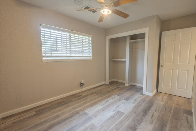 unfurnished bedroom featuring a textured ceiling, a closet, ceiling fan, and light wood-type flooring