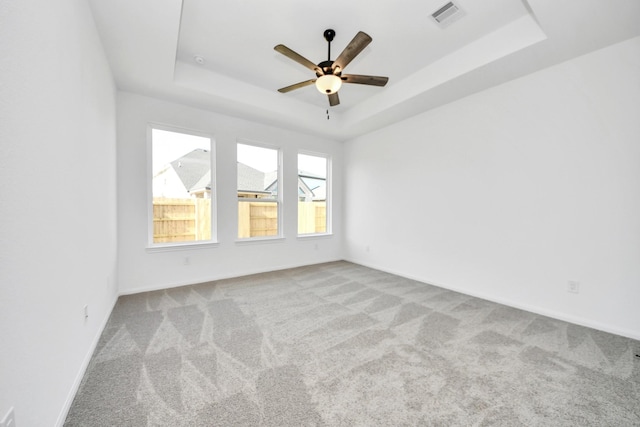 unfurnished room with ceiling fan, light colored carpet, and a raised ceiling