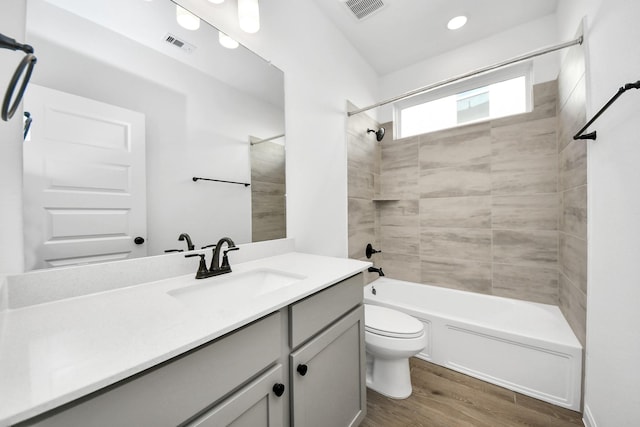 full bathroom featuring wood-type flooring, toilet, tiled shower / bath combo, and vanity