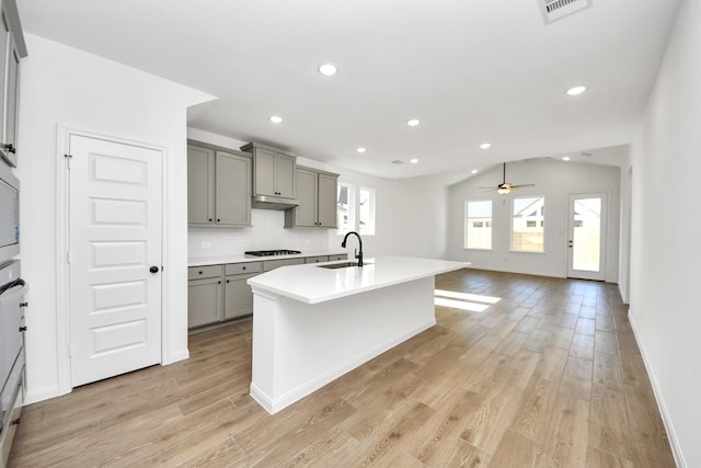 kitchen featuring gray cabinetry, sink, gas stovetop, and an island with sink