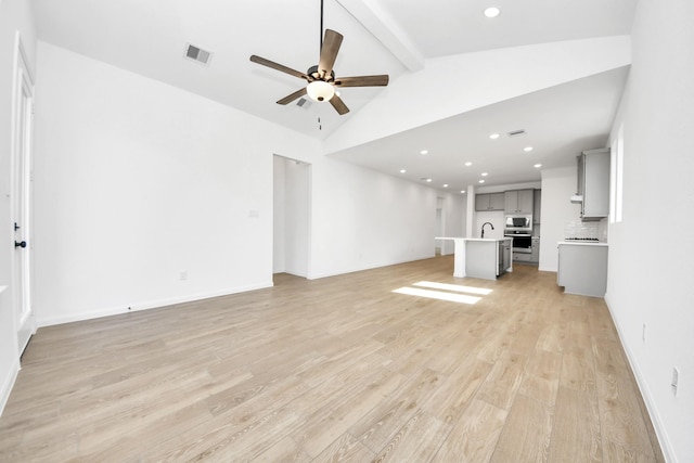 unfurnished living room with sink, lofted ceiling with beams, light hardwood / wood-style floors, and ceiling fan