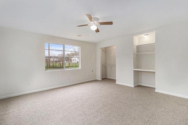 unfurnished bedroom with ceiling fan, a spacious closet, a closet, and carpet