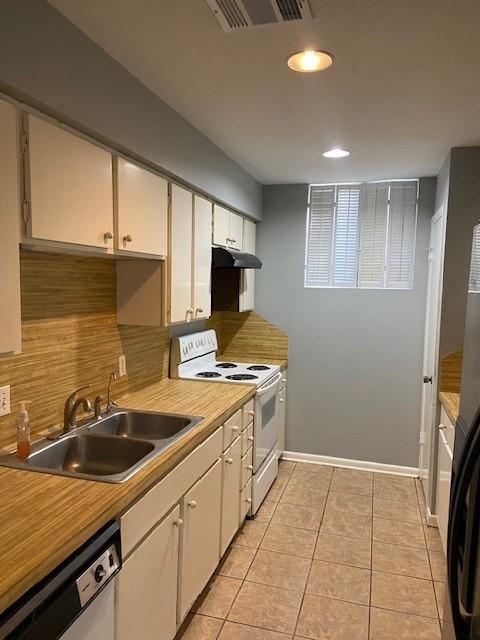 kitchen with light tile patterned flooring, sink, white cabinets, white appliances, and backsplash