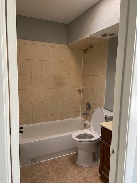 full bathroom with tile patterned flooring, tiled shower / bath, vanity, and toilet