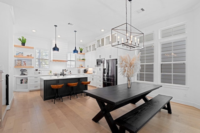 dining space featuring ornamental molding, sink, and light wood-type flooring