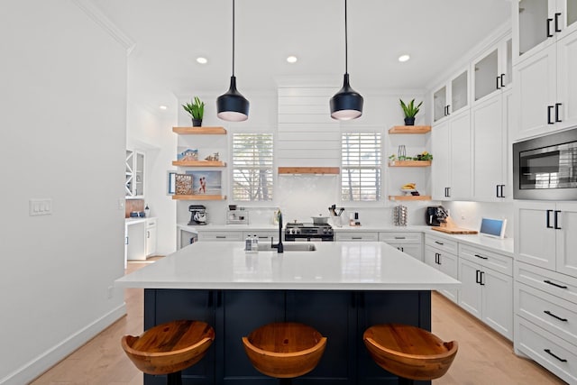 kitchen with pendant lighting, sink, a breakfast bar, appliances with stainless steel finishes, and an island with sink