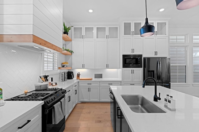 kitchen with pendant lighting, sink, white cabinets, backsplash, and black appliances