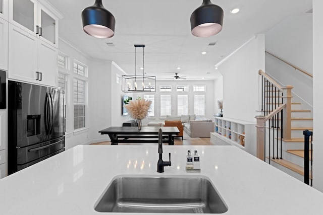 kitchen with sink, crown molding, stainless steel fridge, and white cabinets