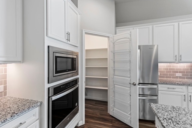 kitchen with white cabinetry, backsplash, stainless steel appliances, dark hardwood / wood-style floors, and light stone countertops