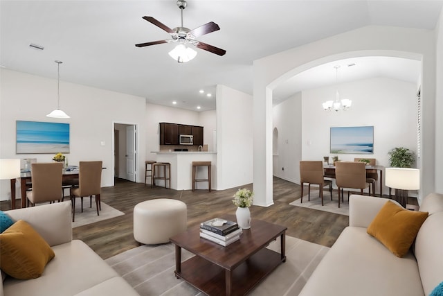 living room with ceiling fan with notable chandelier, dark hardwood / wood-style floors, and vaulted ceiling