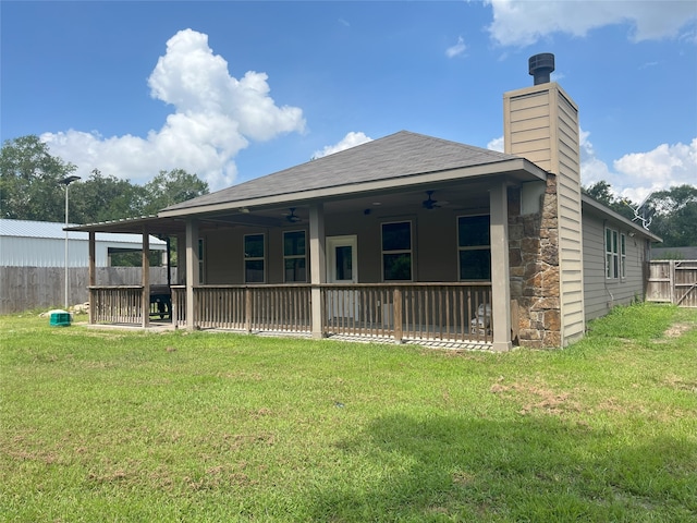 back of house with ceiling fan and a yard