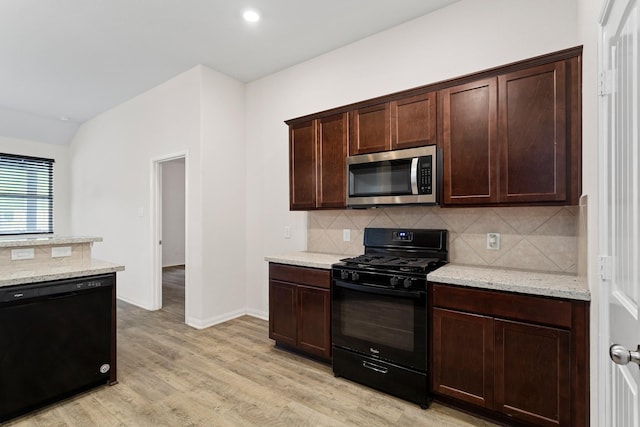 kitchen featuring tasteful backsplash, light stone countertops, light hardwood / wood-style flooring, and black appliances