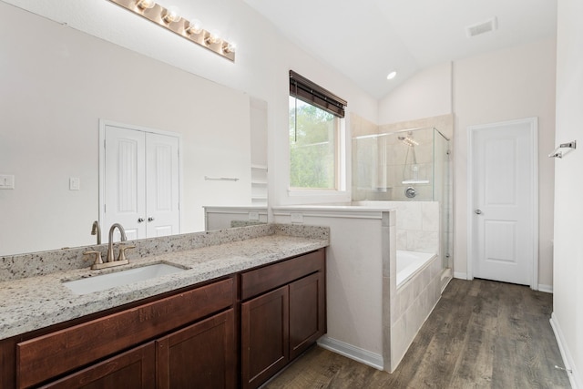 bathroom featuring hardwood / wood-style flooring, vanity, separate shower and tub, and vaulted ceiling