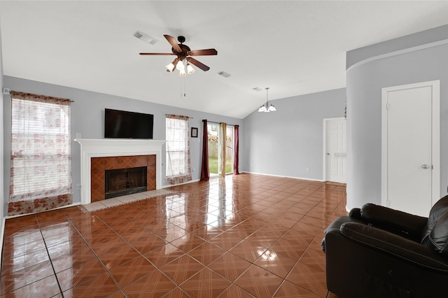 tiled living room featuring a tile fireplace, lofted ceiling, and ceiling fan with notable chandelier