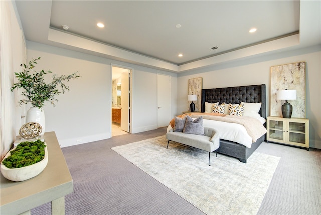 carpeted bedroom with ensuite bathroom and a tray ceiling