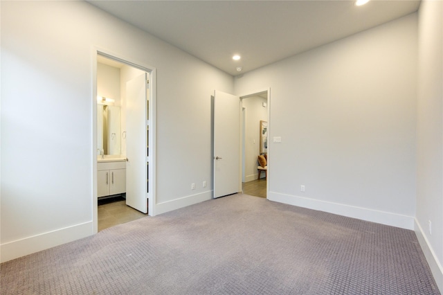 unfurnished bedroom featuring light carpet and connected bathroom