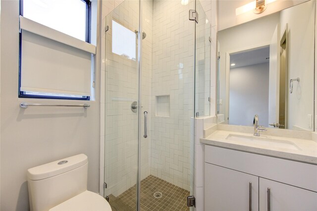 bathroom featuring vanity, a shower with shower door, and toilet