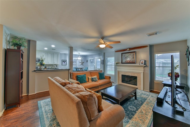 living room featuring ceiling fan, dark hardwood / wood-style floors, and a tile fireplace