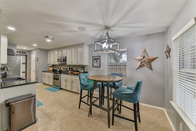 kitchen featuring light tile patterned flooring, sink, appliances with stainless steel finishes, pendant lighting, and backsplash