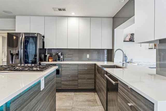 kitchen featuring stainless steel appliances, sink, white cabinets, and light stone counters