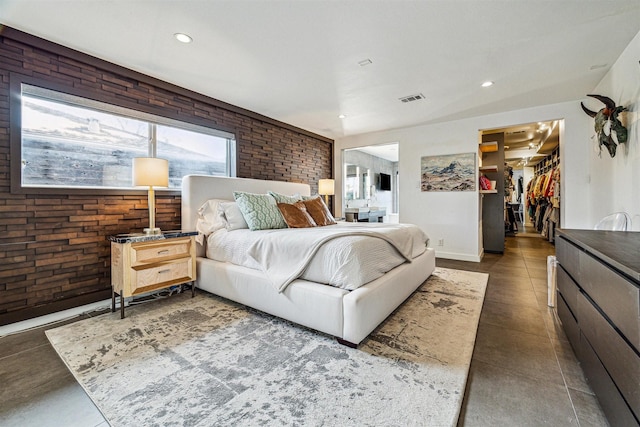 bedroom with a walk in closet, brick wall, and a closet