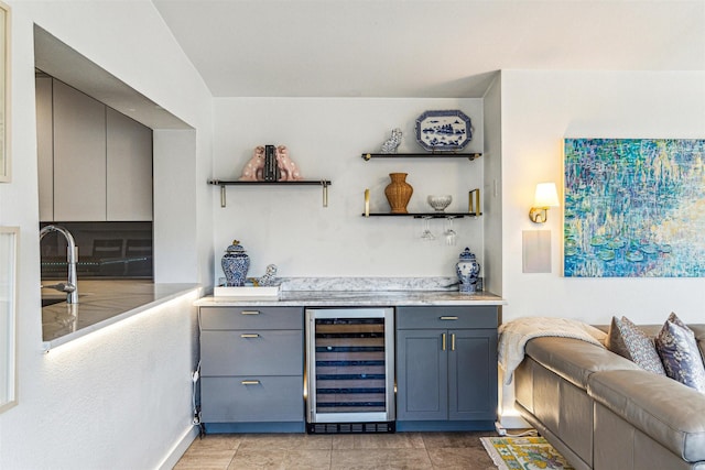 bar featuring beverage cooler, sink, and light tile patterned floors