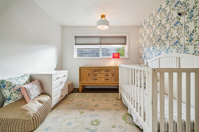 bedroom with a nursery area and light wood-type flooring