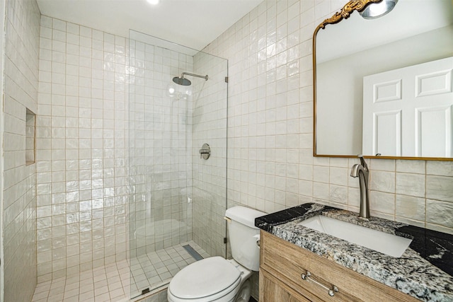 bathroom featuring tiled shower, toilet, tasteful backsplash, tile walls, and vanity