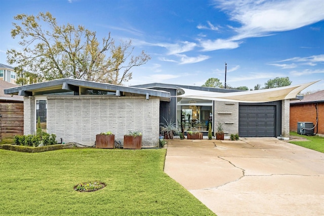 view of front of home with central AC unit, a garage, and a front yard