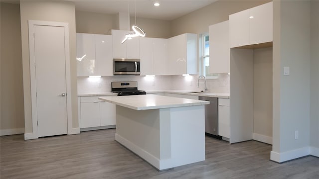 kitchen featuring white cabinetry, decorative light fixtures, stainless steel appliances, and a center island