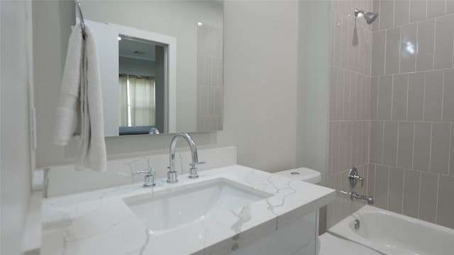 full bathroom with tiled shower / bath, vanity, and toilet