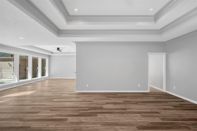 unfurnished room featuring baseboards, a tray ceiling, wood finished floors, and crown molding