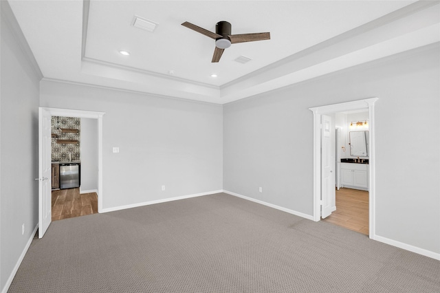 unfurnished bedroom featuring carpet, a raised ceiling, and baseboards