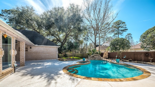 view of swimming pool featuring a fenced backyard, a pool with connected hot tub, and a patio