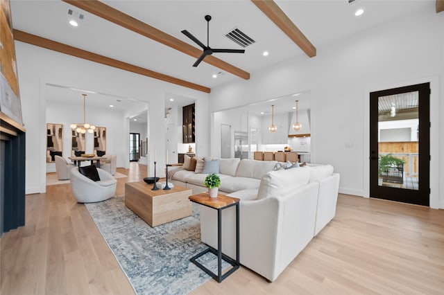 living room featuring a healthy amount of sunlight, ceiling fan, light hardwood / wood-style flooring, and beamed ceiling