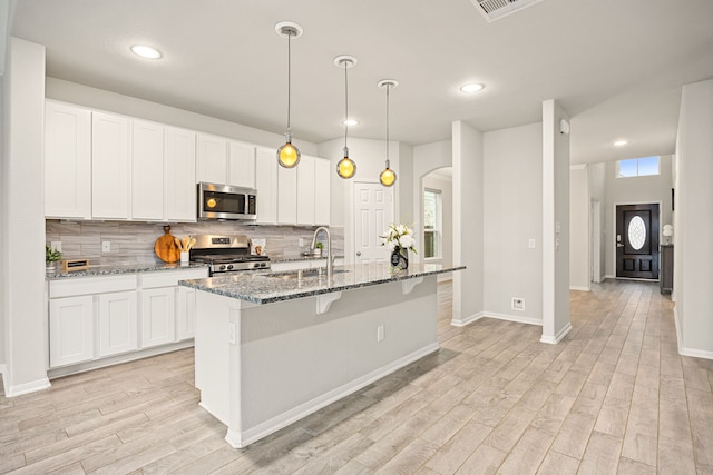 kitchen featuring appliances with stainless steel finishes, sink, dark stone countertops, and white cabinets