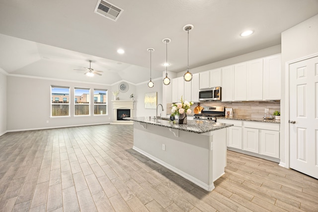 kitchen with stainless steel appliances, hanging light fixtures, white cabinets, and stone counters